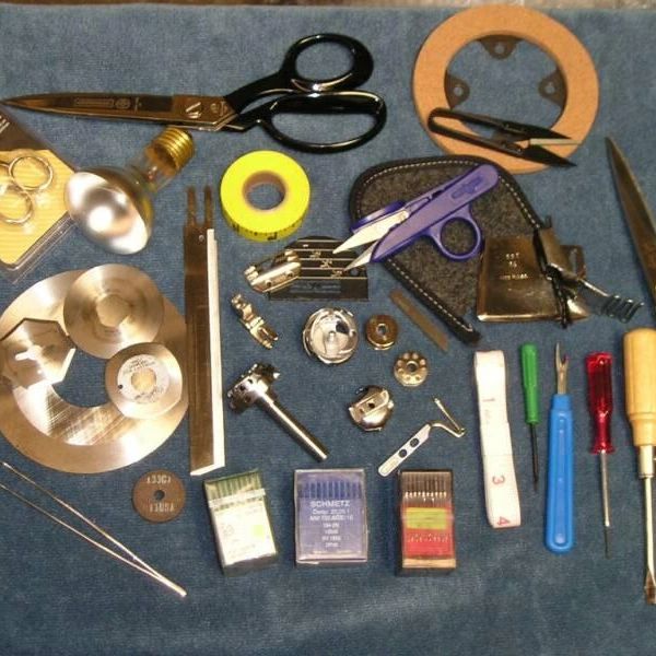 A collection of sewing and repair tools arranged on a blue cloth.
