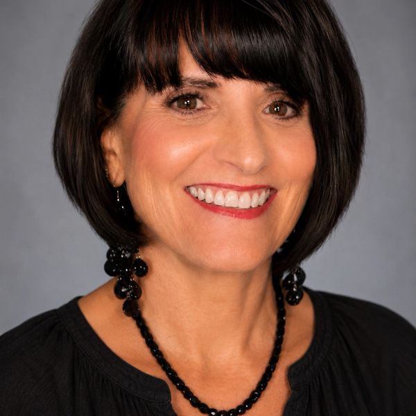 Smiling woman with dark hair and black beaded necklace.