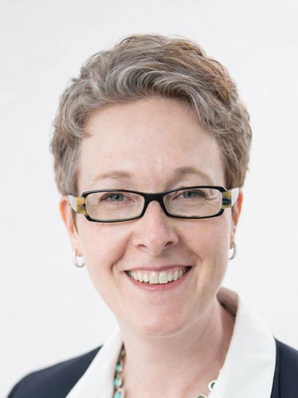 Smiling woman with glasses and short hair.