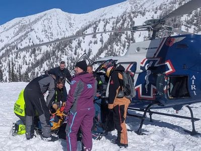 Rescue team evacuates injured person by helicopter in snowy mountains.