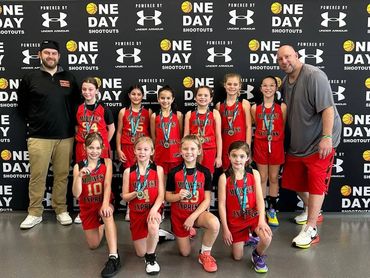 Youth basketball team posing with medals and coaches at a sports event.