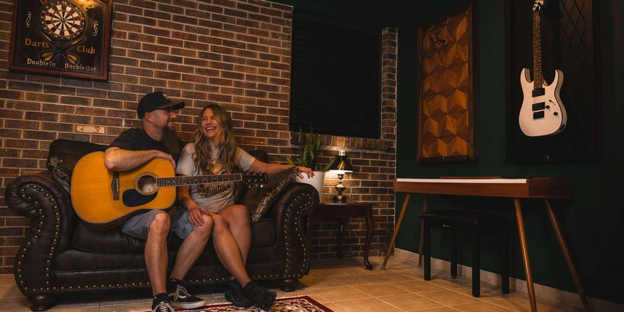 Couple enjoying music time with guitar in cozy room with brick wall.