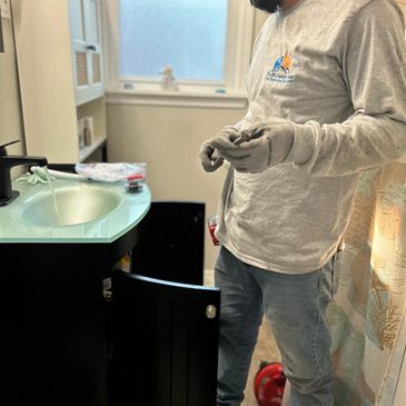 Plumber repairing a bathroom sink with gloves on.