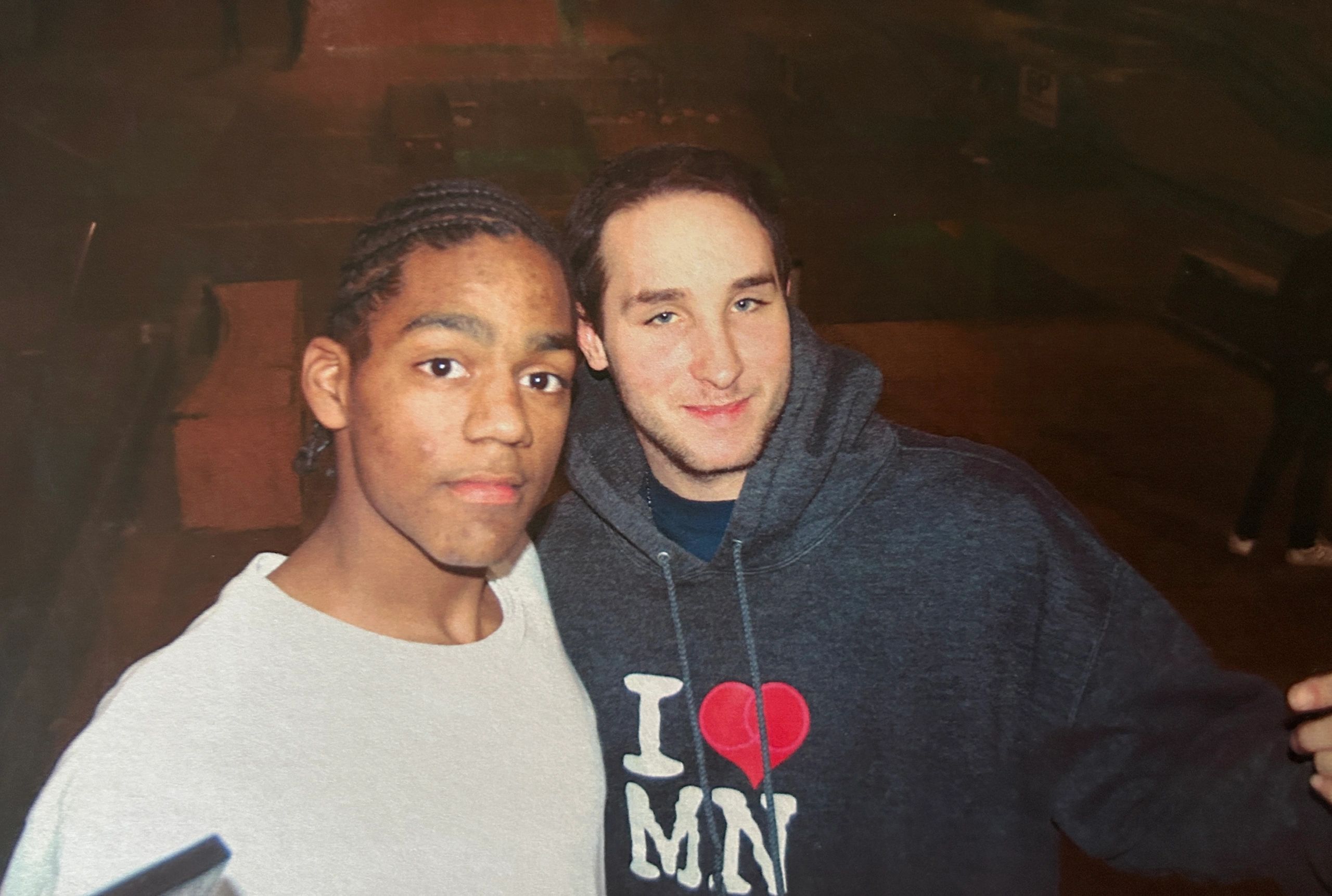 Two young men posing closely for a photo at night.
