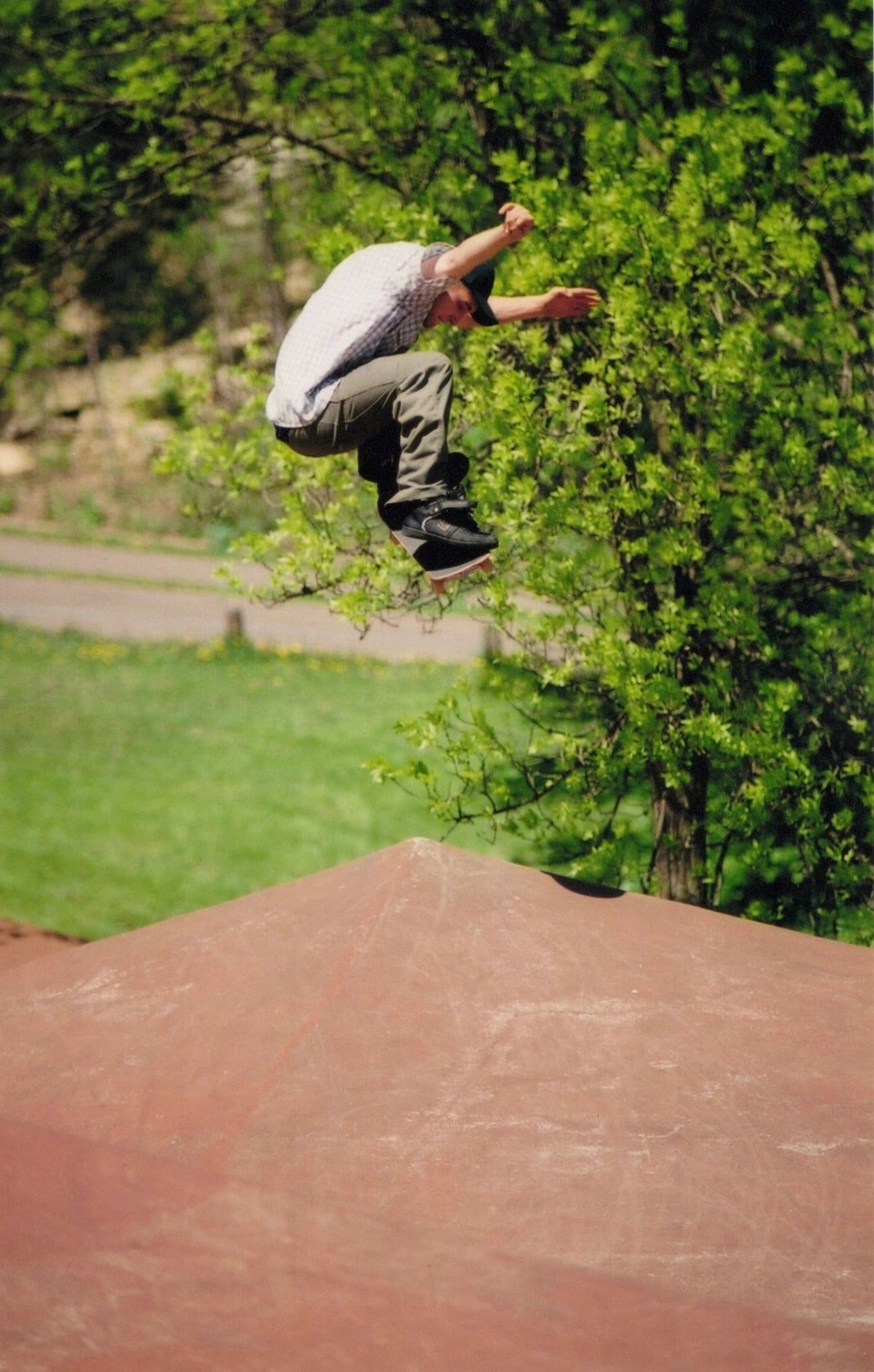 Skateboarder mid-air performing a trick outdoors.