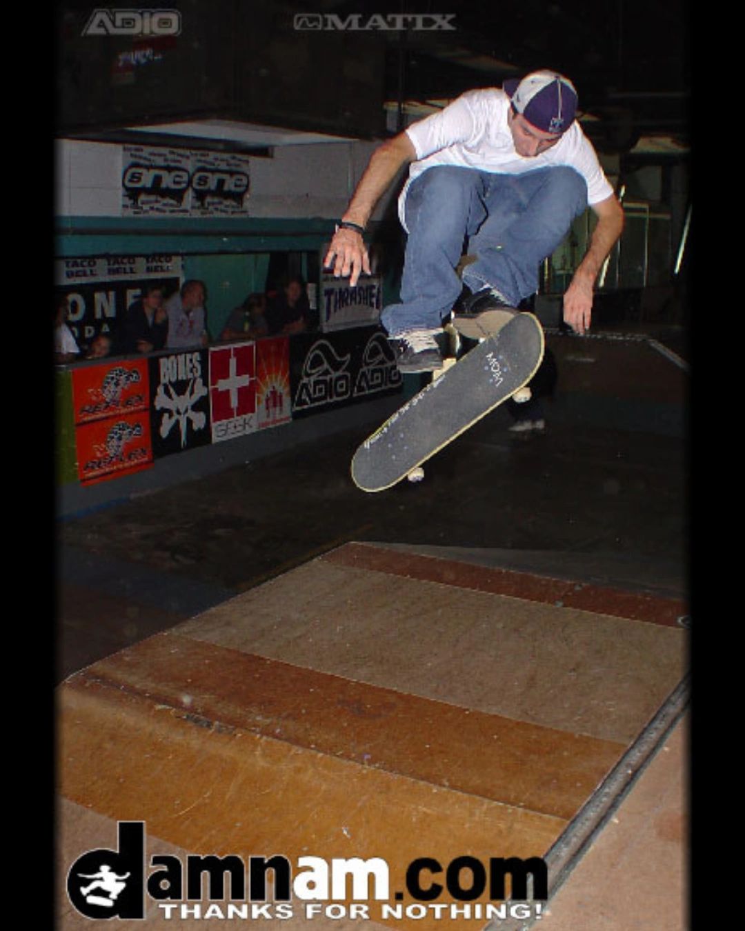 Skateboarder performing a trick indoors at a skate park.