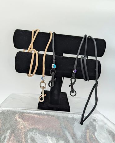 Elegant leather lanyards in beige and black with decorative beads on a display stand.