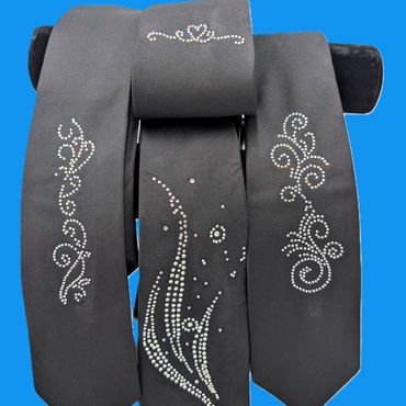 Black fabric pieces with elegant white rhinestone designs on a blue background.