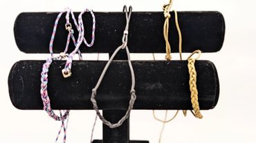 Colorful and gold bracelets displayed on a black stand.