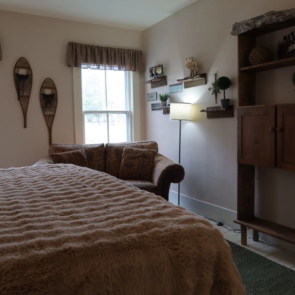 Cozy bedroom with a fluffy blanket, vintage snowshoes, and rustic wooden furniture.