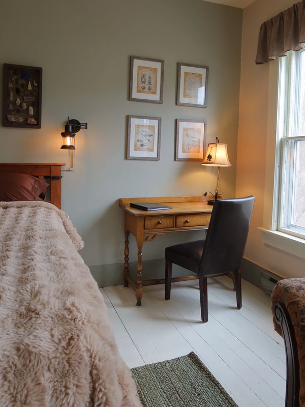 Cozy bedroom corner with wooden desk, leather chair, and soft fur bedspread.