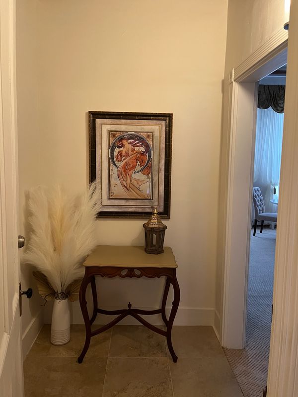 Elegant hallway corner with a vintage table, pampas grass, and framed artwork.