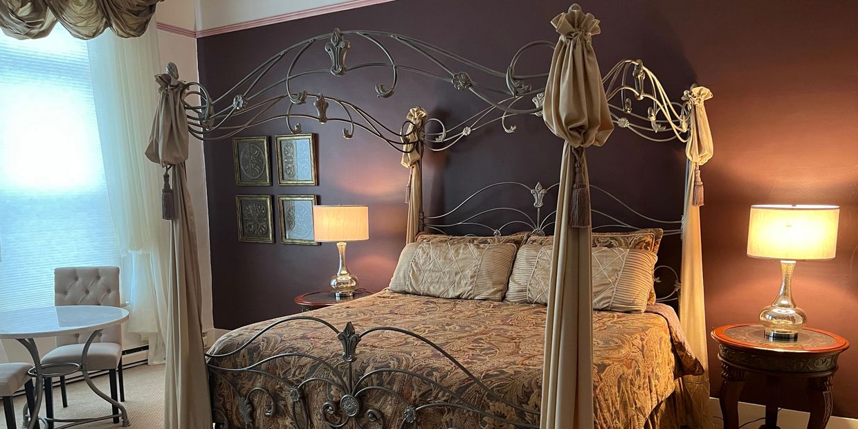 Elegant bedroom with a wrought iron canopy bed and warm lighting.