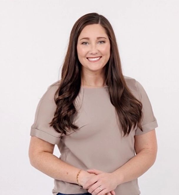 Smiling woman with long brown hair wearing a beige top.
