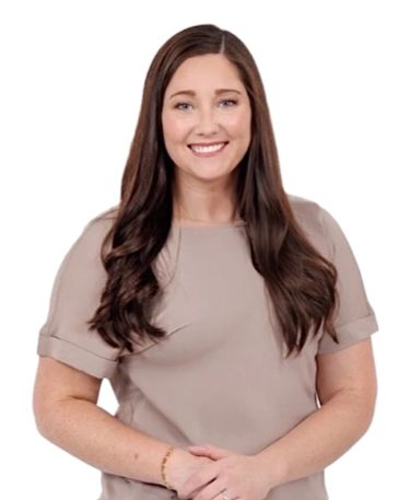 Smiling woman with long brown hair and beige top.