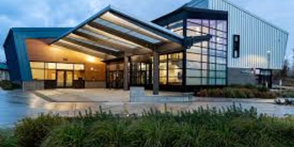 Modern building with glass and metal exterior lit up in evening light.
