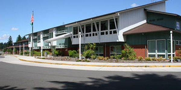 Modern school building with large windows and a flagpole.