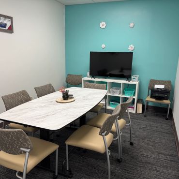 Small office meeting room with teal accent wall and TV.