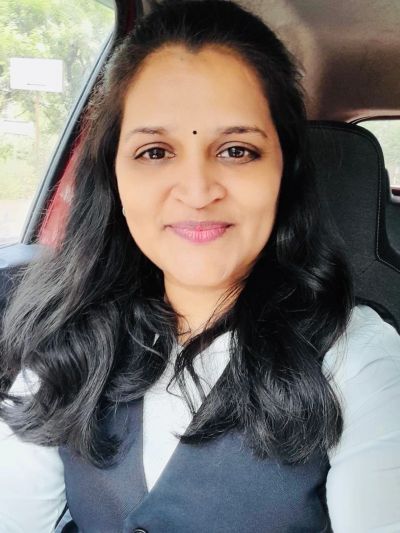 Woman with long black hair sitting in a car, smiling.