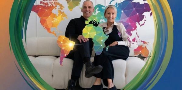 Two people sitting on a couch with a colorful world map background.