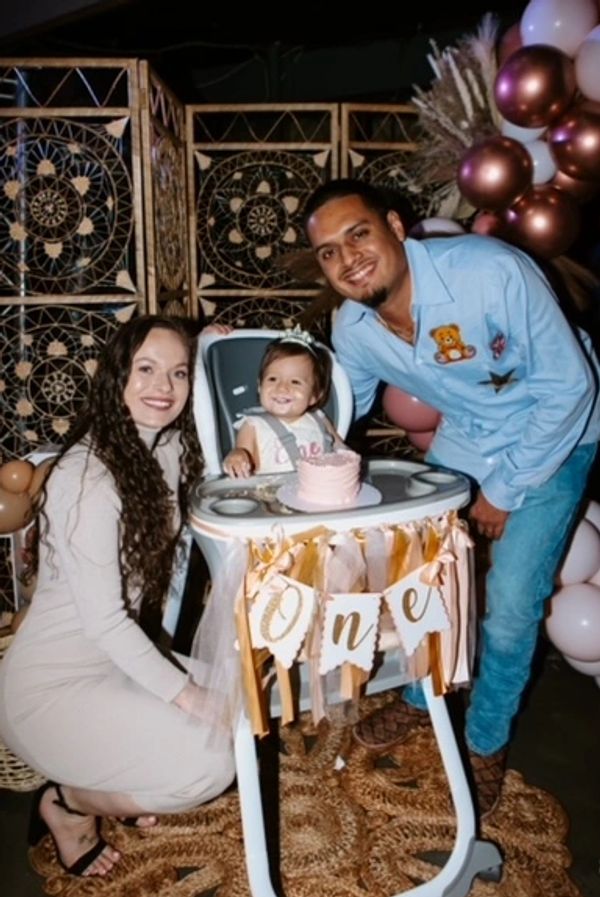 Husband, wife and baby in a highchair one year old birthday party with a boho theme