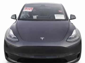 Front view of a black Tesla Model 3 with sale signs on the windshield.