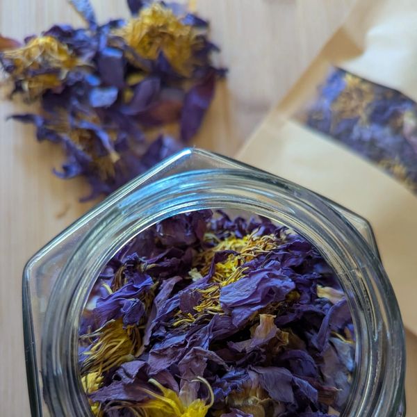 Close-up of dried purple and yellow flowers in a glass jar and packaging.