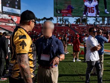 Two men talking on a football field before a game.