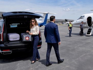 Businesswoman carrying a first aid kit near a car and private jets.