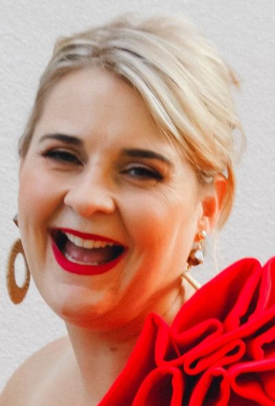 Smiling woman with red lipstick and a red floral dress detail.