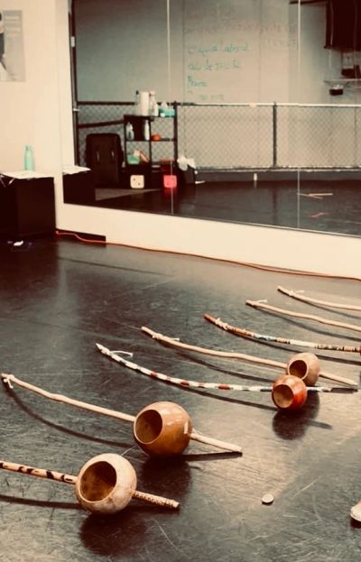 Capoeira berimbaus lined up on a dance studio floor.