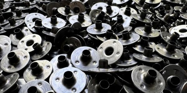 A pile of shiny metal bobbins used in sewing machines.