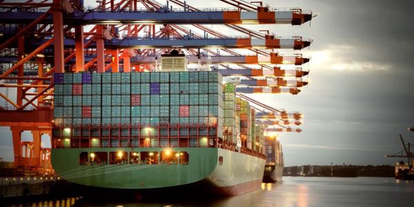 Container ships docked at a busy port with cranes loading and unloading.