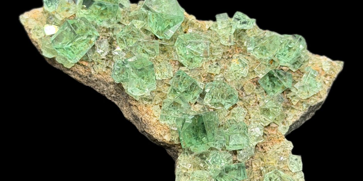 Green cubic crystals on a rough rock base.