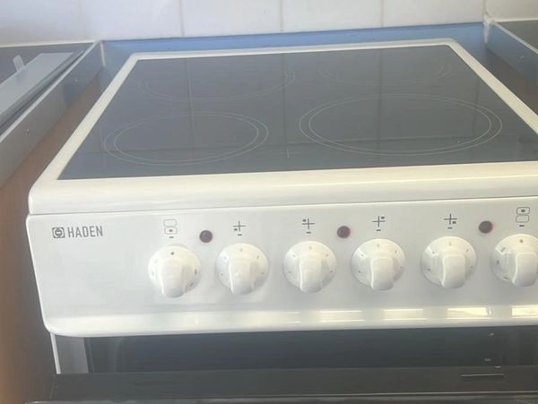 White Haden electric stove with six control knobs and smooth glass cooktop.