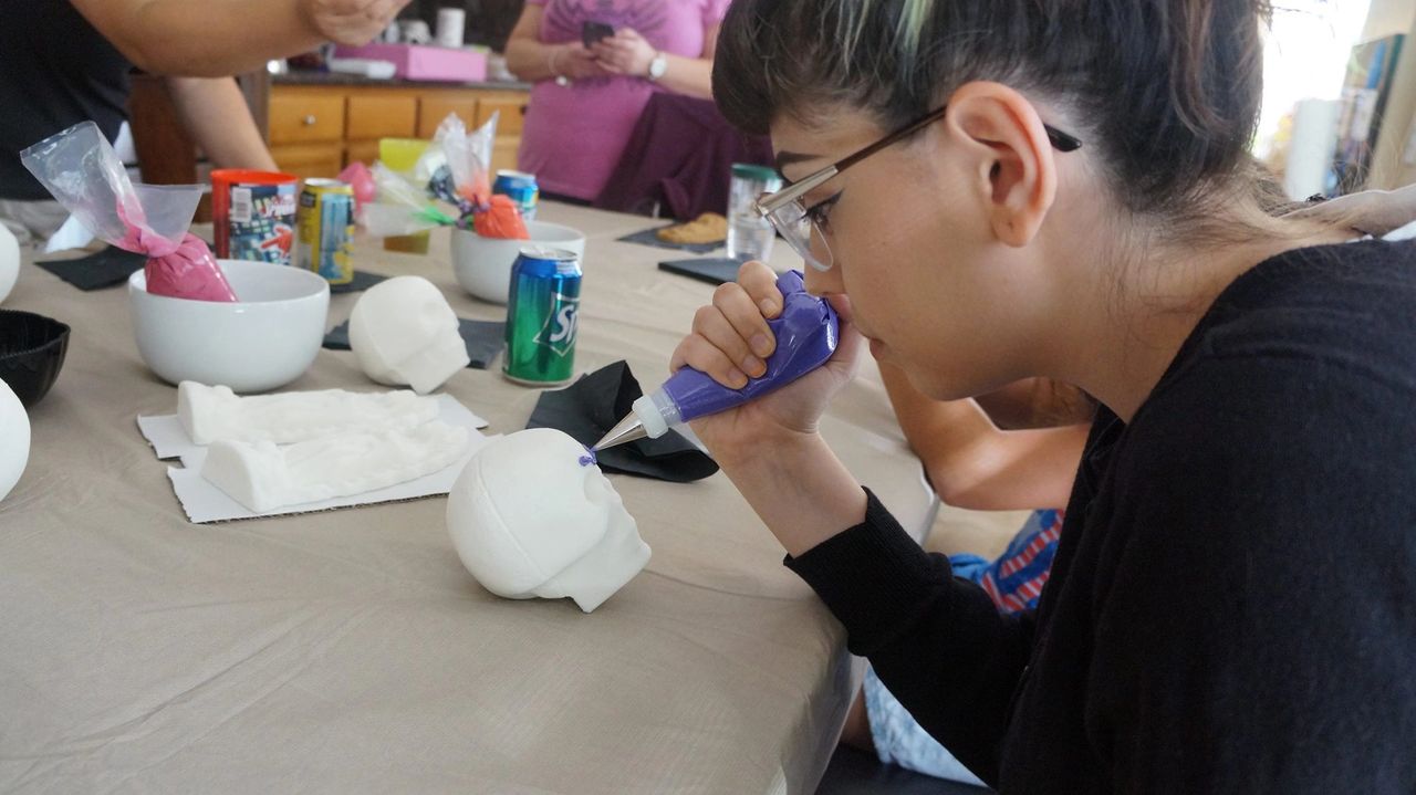 Girl decorating a sugar skull with royal icing.