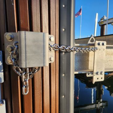 A heavy-duty metal chain locked to a wooden and metal structure near water.
