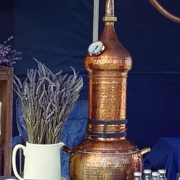 A stall selling lavender bags and bunches with a copper still in the centre of the table