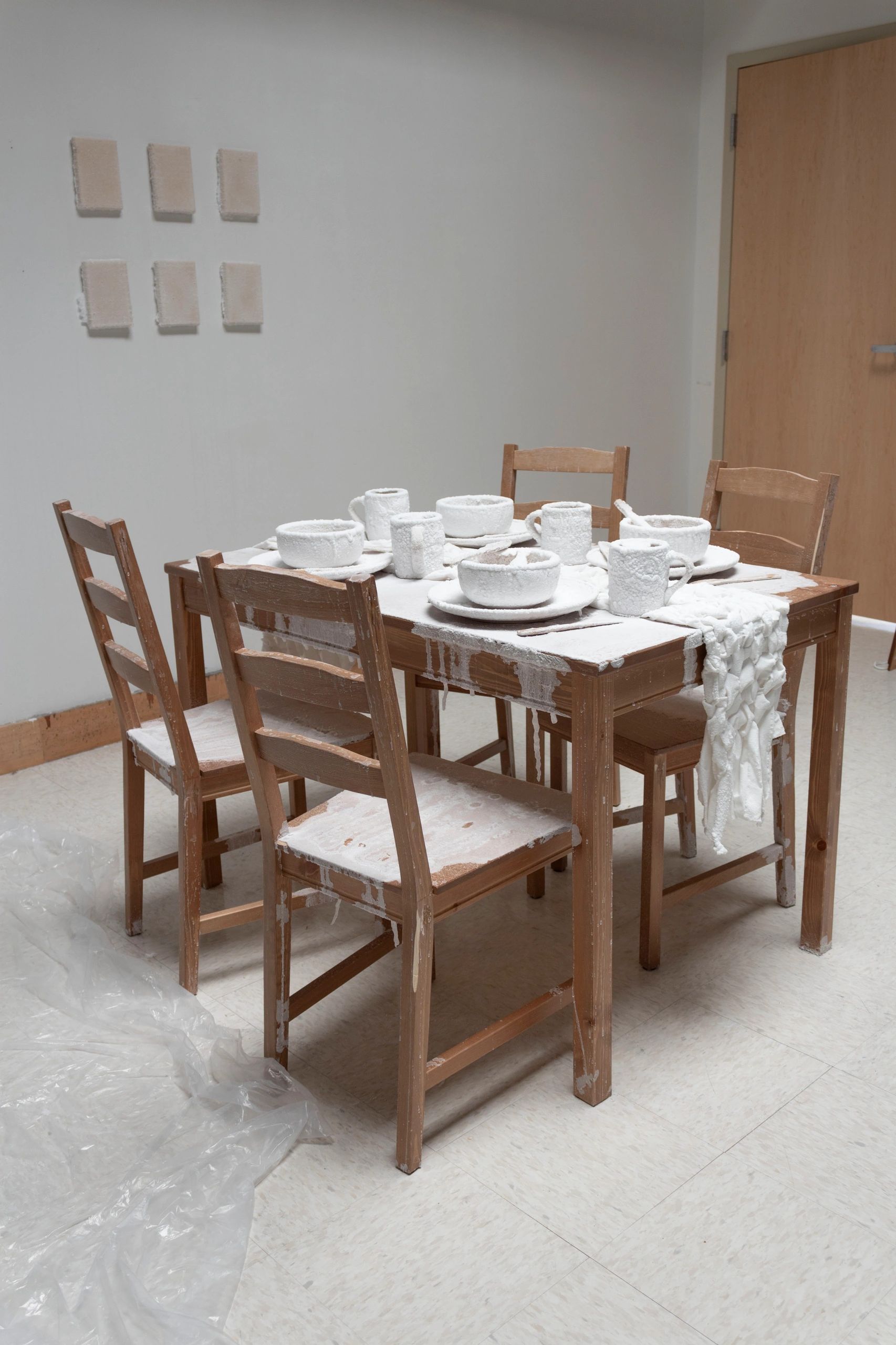 Photograph of a kitchen table with four chairs  with white, salt encrusted dishes