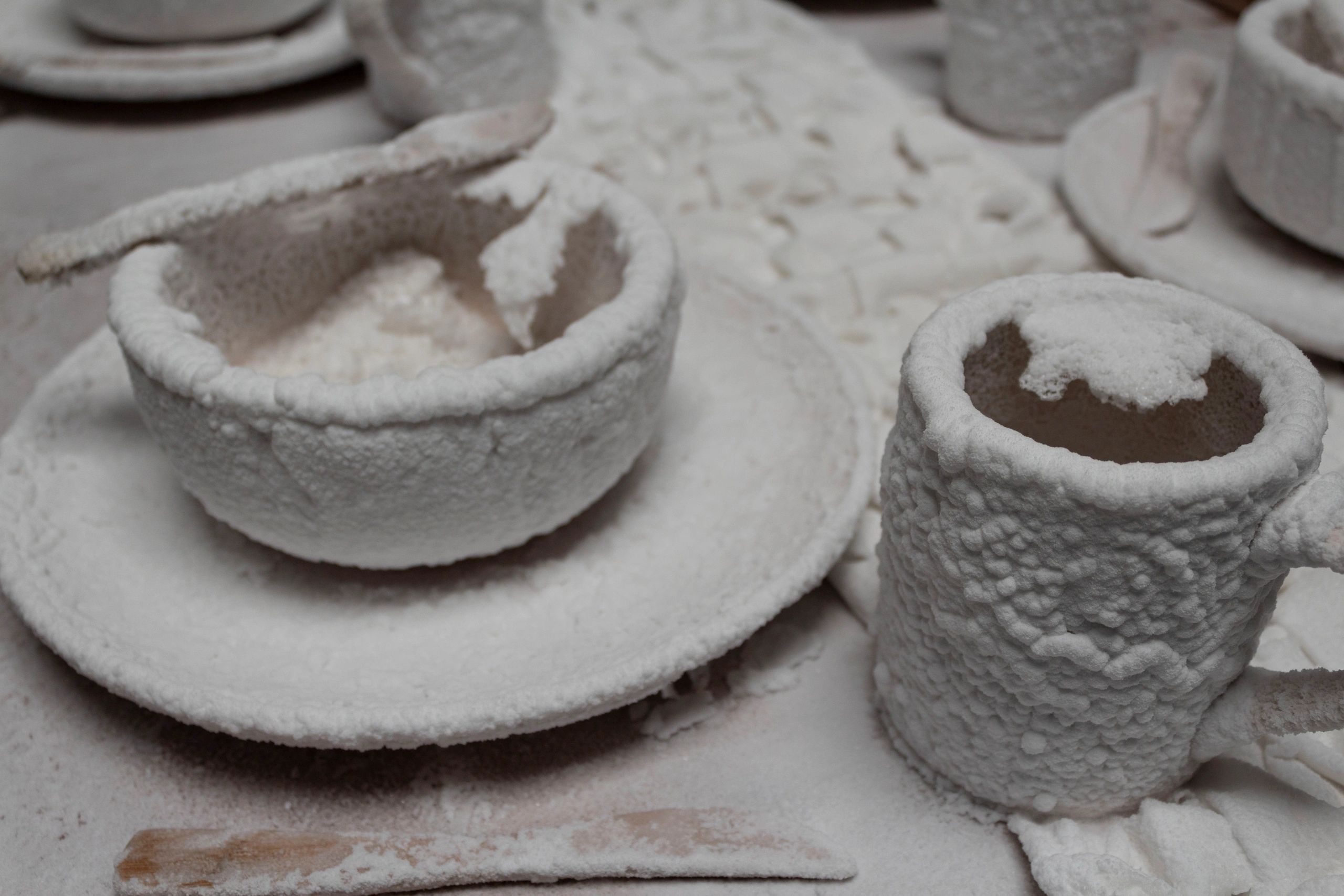 Photograph of a plate, bowl, and mug encrusted in salt crystals on a table