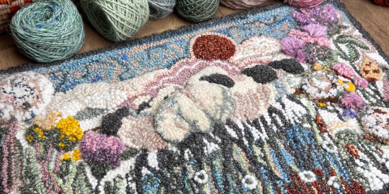 Colorful handmade rug with yarn balls on a wooden table.