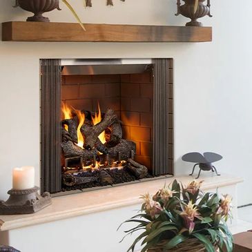Cozy lit fireplace with candle and flowers.