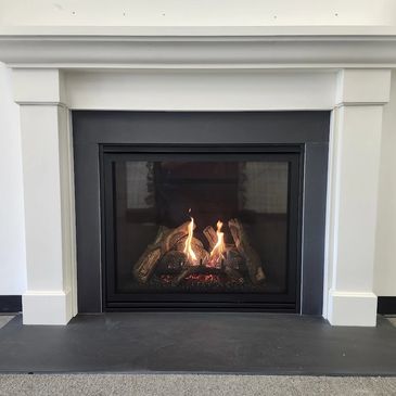 Modern fireplace with a cozy fire burning inside a black metal frame.