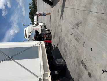 A truck with its trailer detached and a person standing nearby on a sunny day.