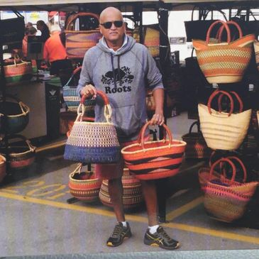 Man holding wicker baskets at a market stall.