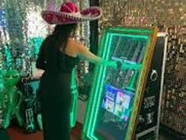 Woman in a sombrero using an interactive photo booth with green lights.