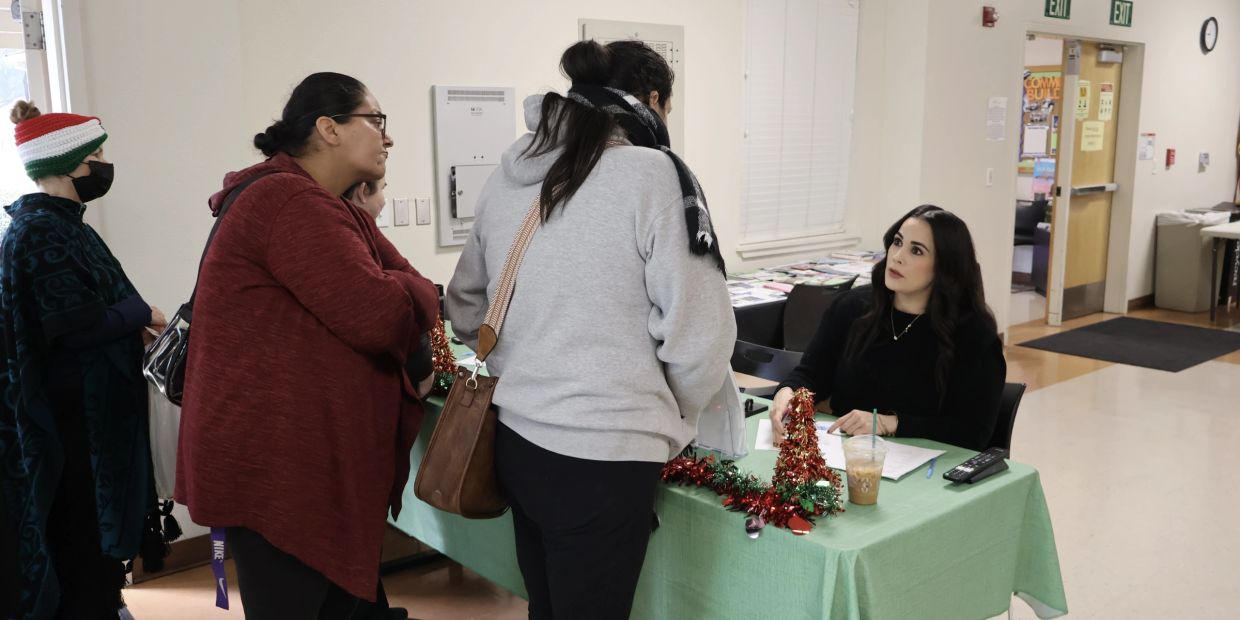 People interacting at a table decorated for the holidays in an indoor setting.