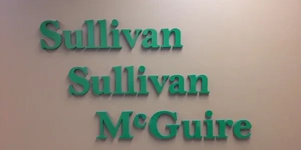 Green 3D letters on wall spell 'Sullivan Sullivan McGuire'.