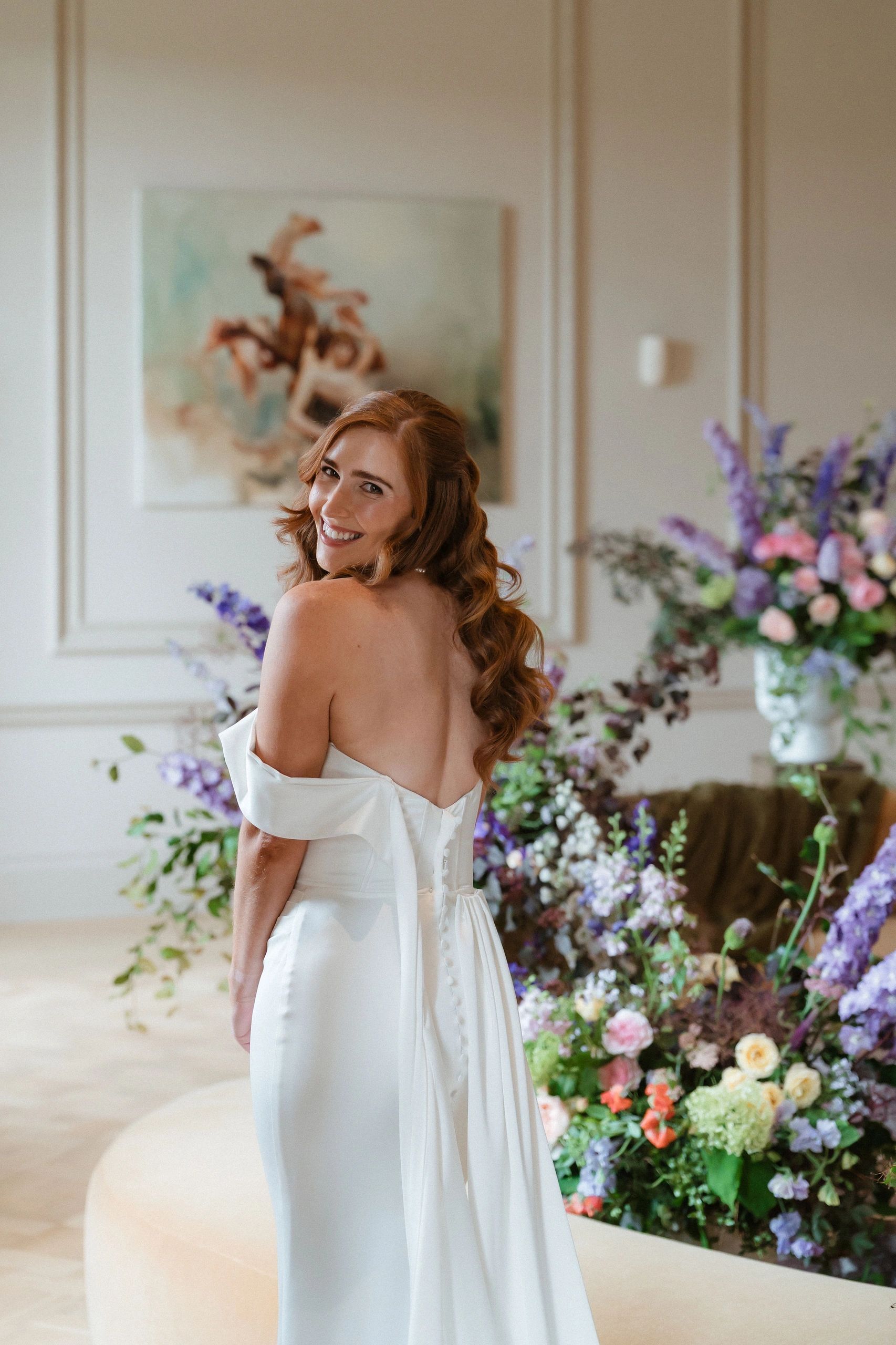 Happy bride in white dress, standing next to floral displays