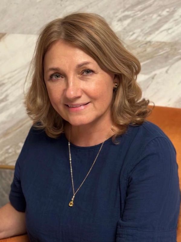 Smiling woman with shoulder-length hair in a blue top.